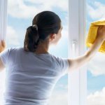 Femme lave la fenêtre par temps ensoleillé